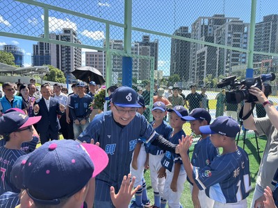 圖說： 新北市長侯友宜(中)與興穀國小棒球隊開心擊掌，為友誼賽熱身，體驗嶄新的運動場地。