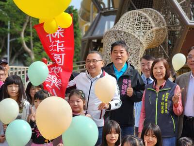 侯友宜市長(穿白外套)宣布新莊區快樂公園正式啟用，與孩童開心合照，氣氛充滿歡樂。