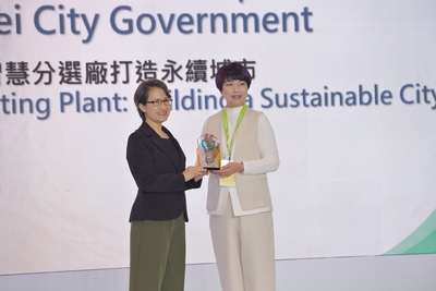 新北市政府「建築執照AI輔助審查」及「AI智慧分選廠打造永續城市」，榮獲智慧城市創新應用獎，副總統蕭美琴（左）頒發表揚，新北市政府副秘書長龔雅雯（右）代表市府團隊領獎。